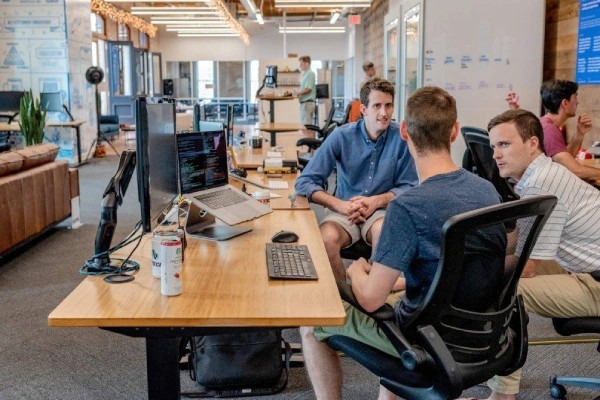 Three man sitting at a table with a laptop.